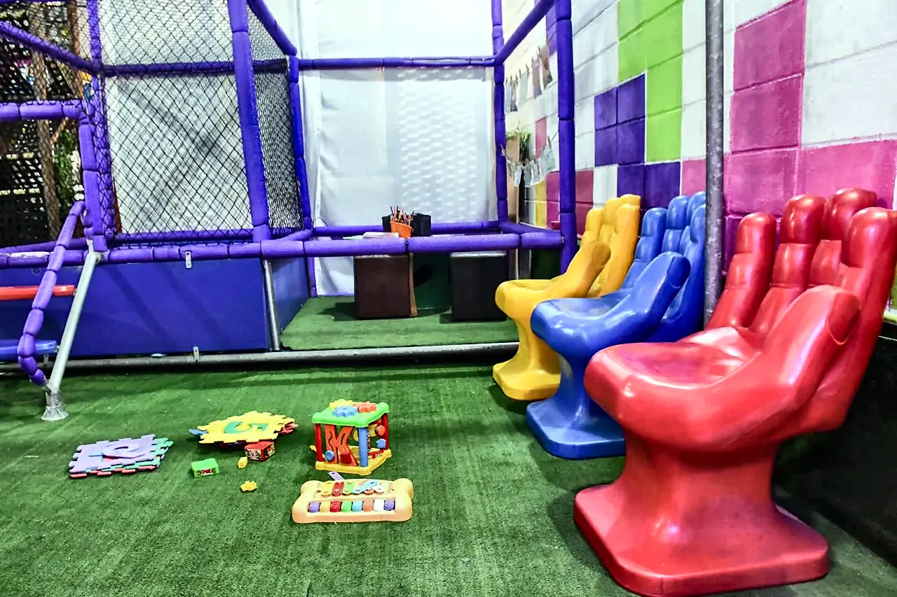 Espaço Baby com grama sintética, brinquedos educativos e poltronas coloridas em formato de mão