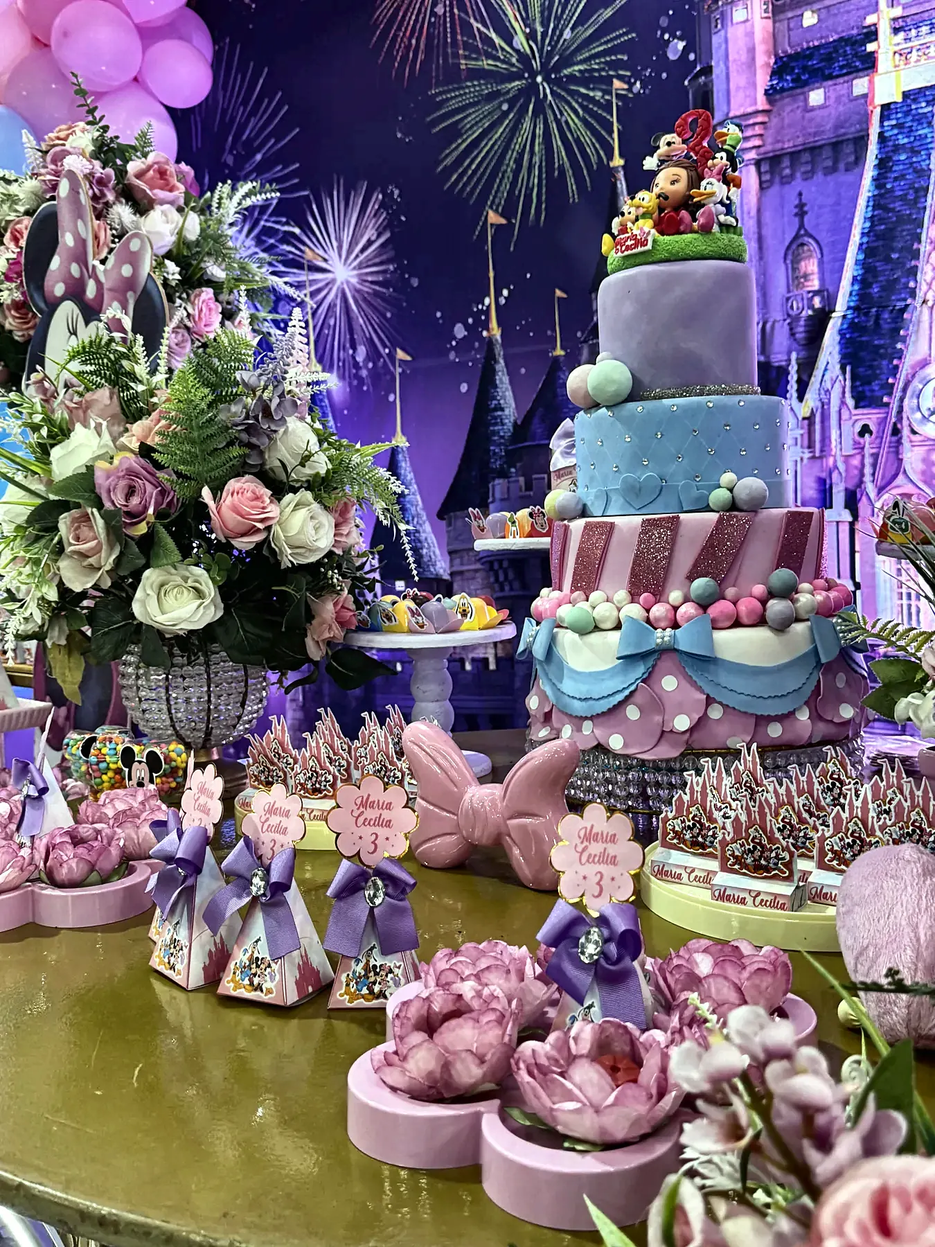 Mesa do bolo montada com flores, doces e painel iluminado