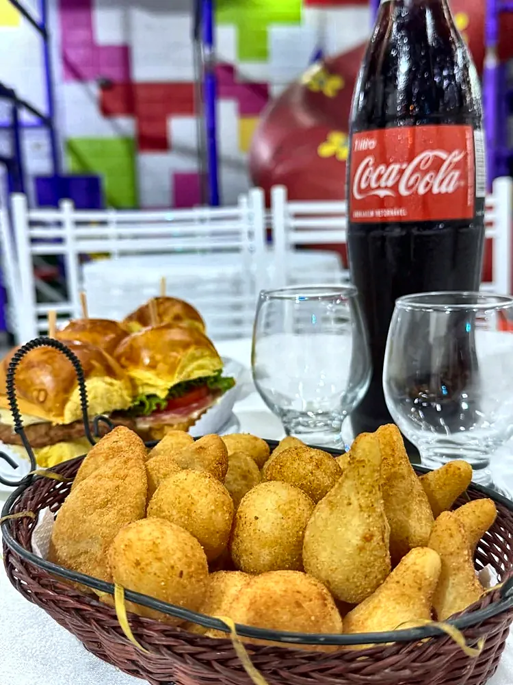 Mesa de convidados com cesta de salgados, taças e bebidas
